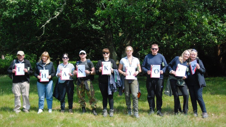 A corporate conservation and wellness team day out on Brownsea, team holding up thank you cards.